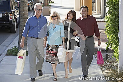 Couples With Shopping Bags Walking On Sidewalk