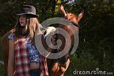 Cowgirl in hat with bay horse