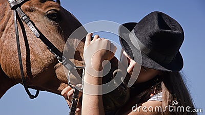 Cowgirl in hat with bay horse