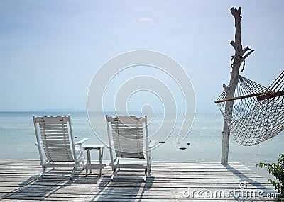 Cozy white beach chair and hammock facing seascape