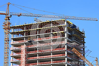 Crane and high-rise building under construction against blue sky.