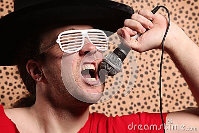 Crazy rock and roller singer with a big black hat, party glasses in front of a cheetah skin background