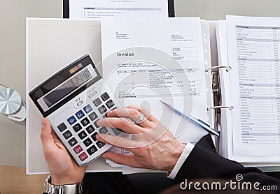 Cropped image of businessman calculating invoice at desk
