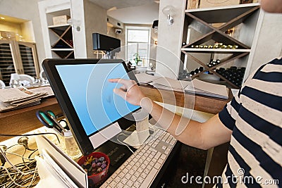 Cropped image of cashier touching computer screen at restaurant counter
