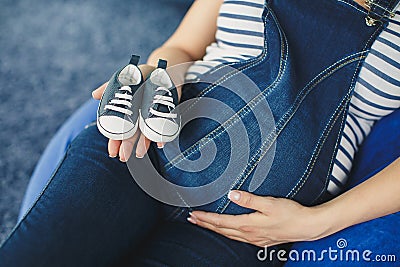Cropped image of a pregnant woman little shoes