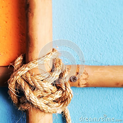 Cross bamboo bars with rope tied on the vintage wall background.