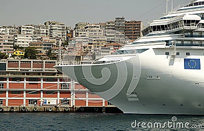 Cruise ship docked at terminal with city on back