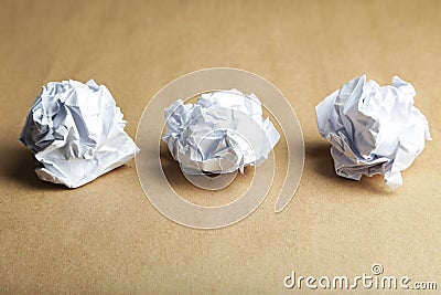 Crumpled paper ball on brown background.