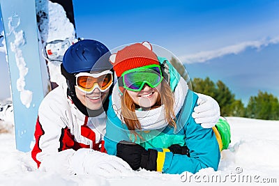 Cuddling couple in ski masks lying on the snow