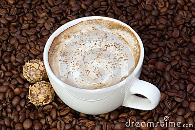 Cup of coffee and candies on a coffee beans background