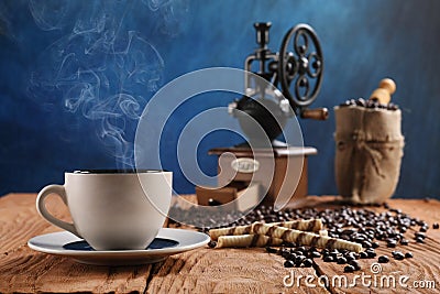 Cup of coffee, coffee grinder, coffee beans in a sack