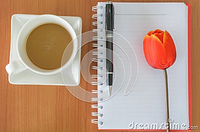 Cup of coffee with notebook and flower