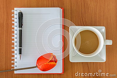 Cup of coffee with notebook and flower