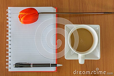 Cup of coffee with notebook and flower