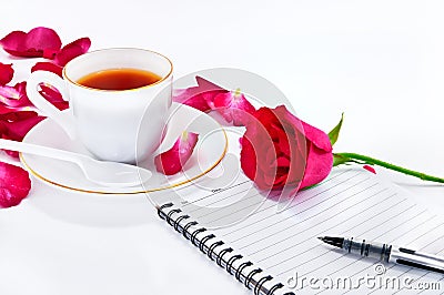 Cup of coffee with red roses and notebook