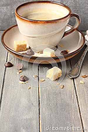 Cup of coffee, sugar cubes and chocolate drops on old wooden background with copy space