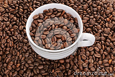 A cup full of coffee beans surrounded by coffee beans