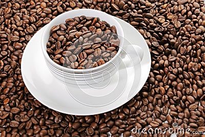 A cup full of coffee beans surrounded by coffee beans