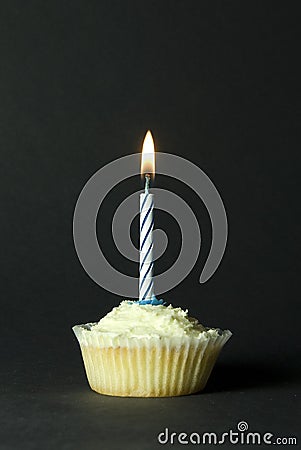 Cupcake with blue candle on black background