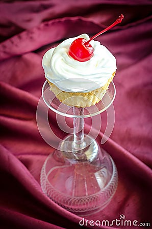 Cupcake with whipped cream and maraschino cherry