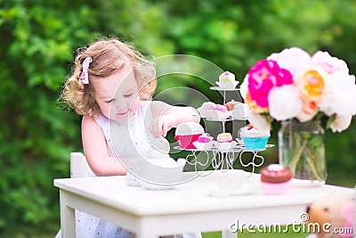 Curly cute toddler girl playing tea party with a doll