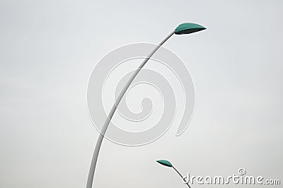 Curved street-lamps leaning their green heads towards each other