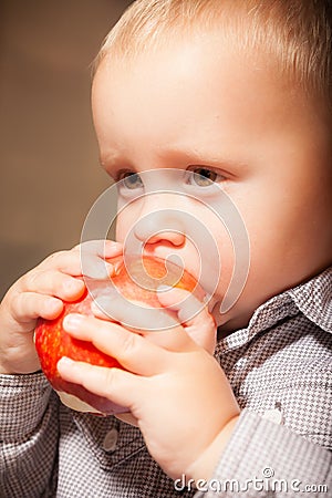 Cute baby boy eating red apple fruit