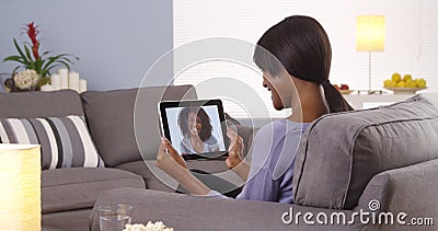 Cute black woman talking with friend on tablet