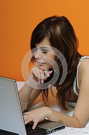 Cute brunette girl using laptop in bed