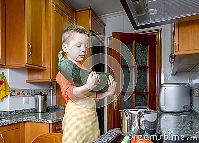 Cute child chef cooking big zucchini in a pot