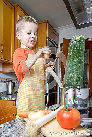 Cute child chef cooking big zucchini in a pot