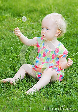 Cute funny baby girl sitting on grass with flowers