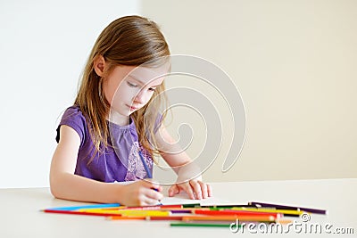 Cute girl drawing a picture with colorful pencils