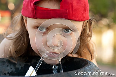 Cute girl drinking from a water fountain