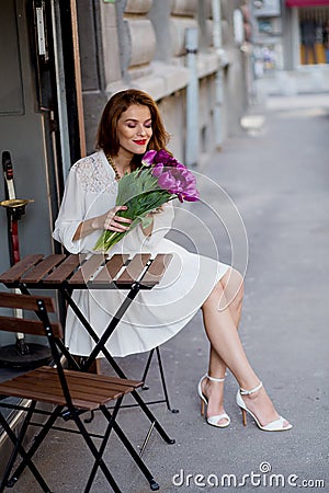 Cute girl in white dress and a beautiful bouquet of tulips.