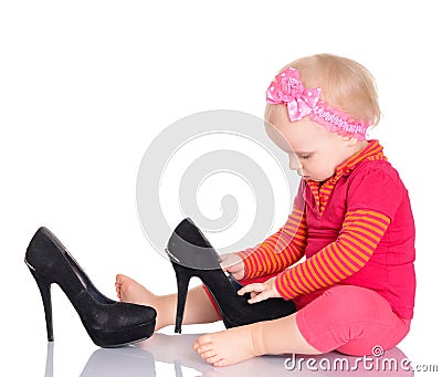 Cute little baby girl trying on her mother s shoes on white back