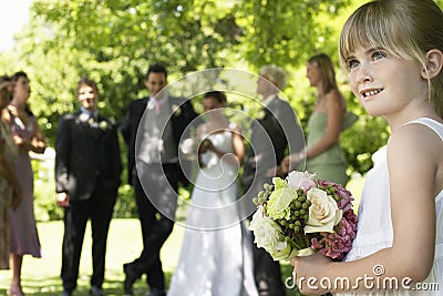 Cute Little Bridesmaid Holding Bouquet In Lawn