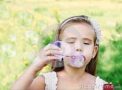 Cute little girl is blowing a soap bubbles