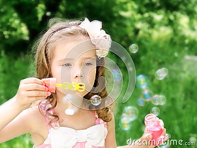 Cute little girl is blowing a soap bubbles