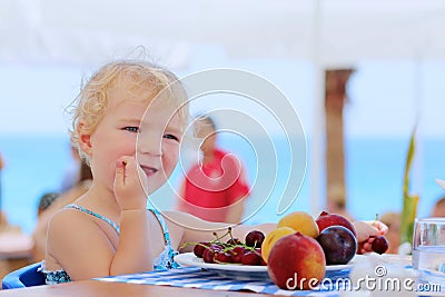 Cute little girl eating fruits in resort restaurant