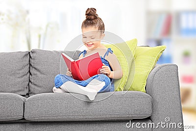 Cute little girl reading a book in the living room