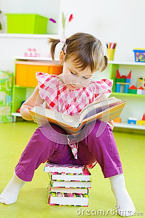 Cute little girl reading book sitting on floor