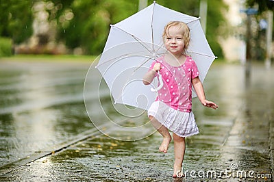 Cute little toddler girl having fun under a rain