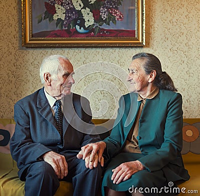 Cute 80 plus year old married couple posing for a portrait in their house. Love forever concept