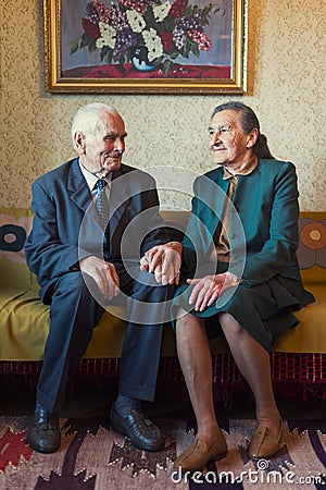 Cute 80 plus year old married couple posing for a portrait in their house. Love forever concept