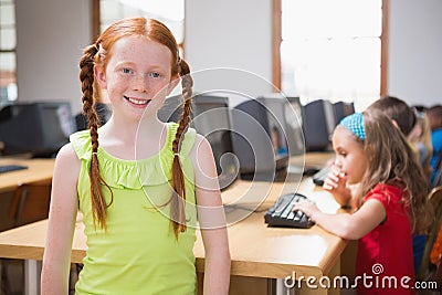 Cute pupil in computer class smiling at camera
