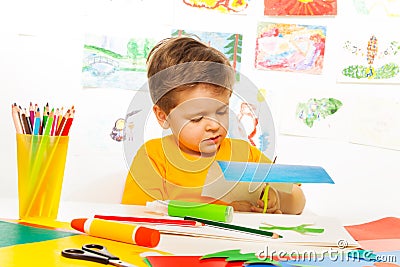 Cute small boy crafting and sitting at the table