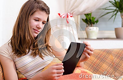 Cute teenage girl reading novels on ebook reader