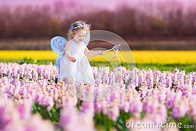 Cute toddler girl in fairy costume in a flower field