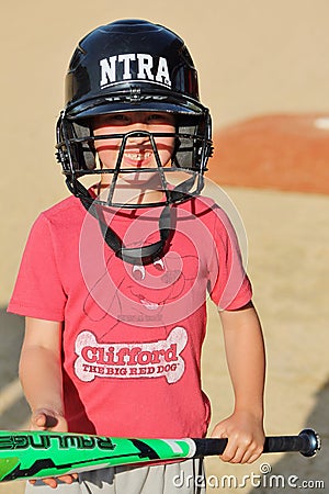 Cute young boy in a baseball helmet holding a bat